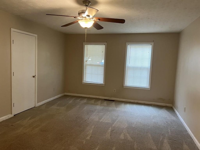 unfurnished room with ceiling fan, a textured ceiling, and carpet