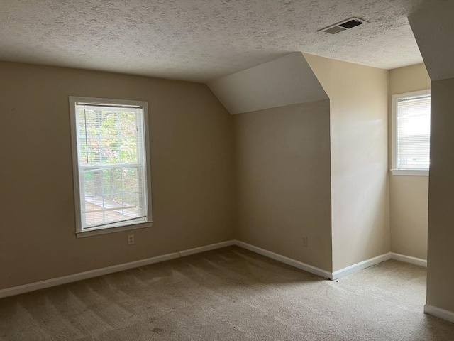 bonus room featuring plenty of natural light, a textured ceiling, lofted ceiling, and carpet floors