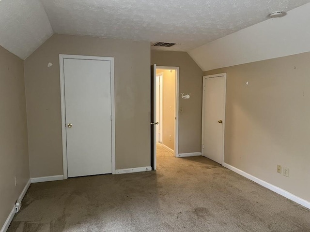 bonus room with a textured ceiling, light colored carpet, and vaulted ceiling