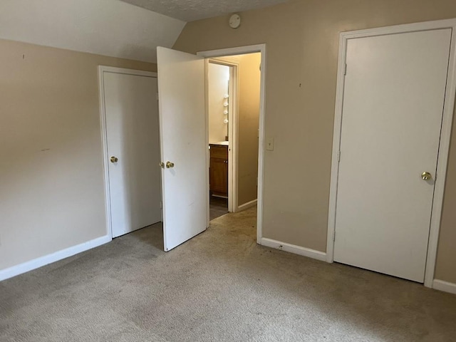 unfurnished bedroom featuring lofted ceiling and light carpet