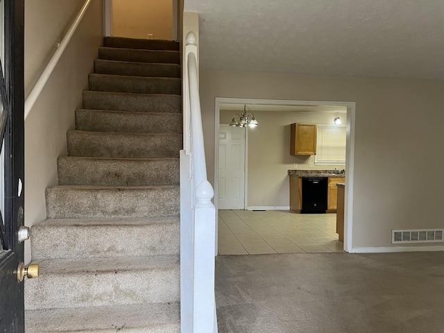 stairs with tile patterned flooring, an inviting chandelier, and a textured ceiling