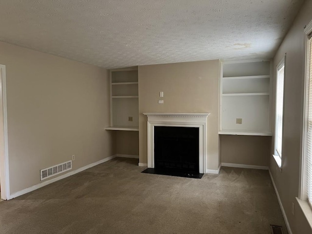 unfurnished living room with a textured ceiling and carpet flooring