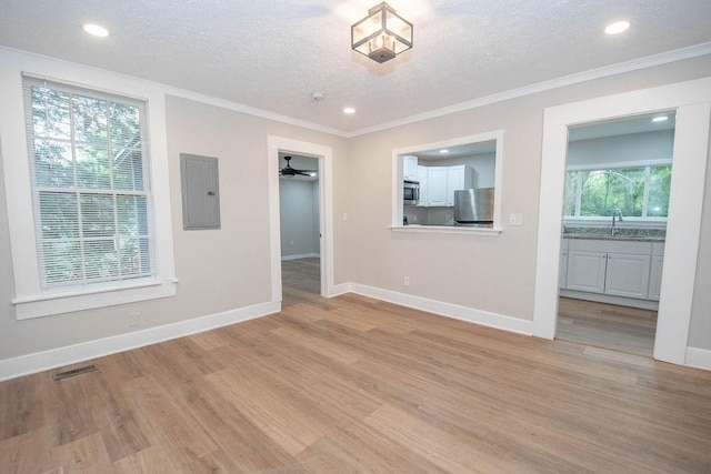 1402 Elm St, Lagrange, GA 30240 - unfurnished living room featuring a textured ceiling, baseboards, light wood-type flooring, ornamental molding, and electric panel
