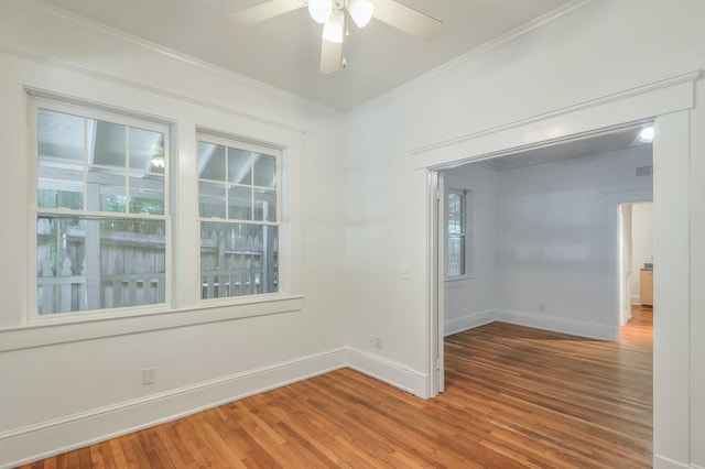 empty room with wood finished floors, baseboards, ceiling fan, and crown molding