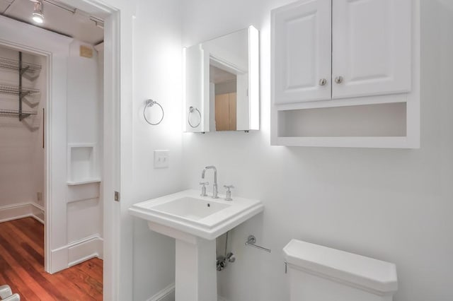 half bath featuring toilet, wood finished floors, and baseboards