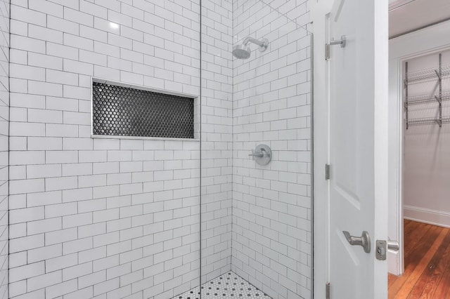 bathroom with a shower stall, wood finished floors, and a walk in closet