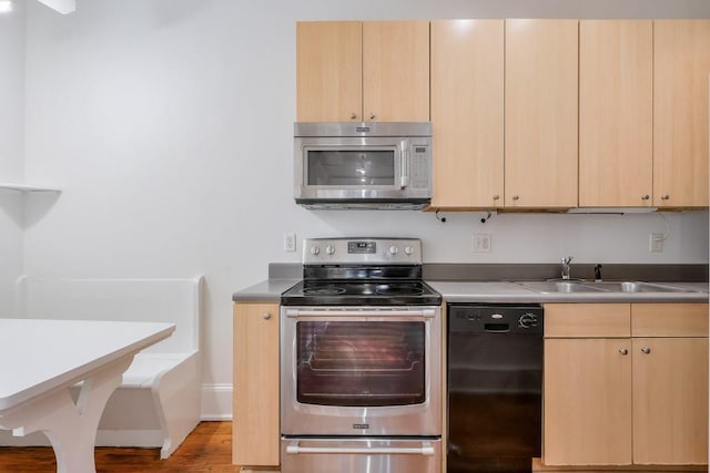 kitchen with appliances with stainless steel finishes, light brown cabinets, a sink, and light wood-style flooring