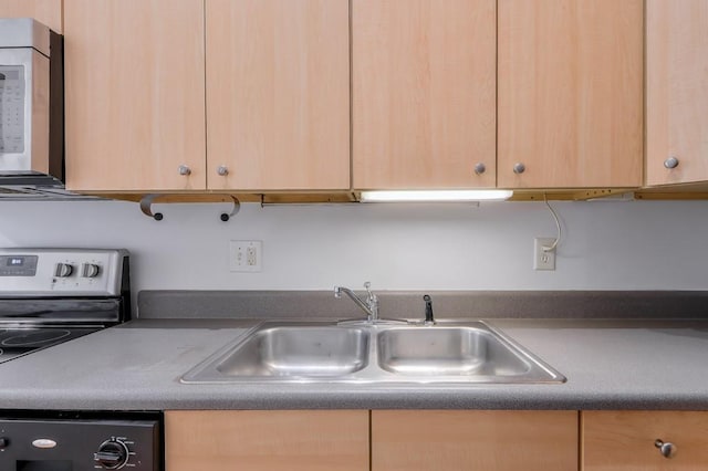 kitchen featuring light brown cabinets, a sink, appliances with stainless steel finishes, and dark countertops