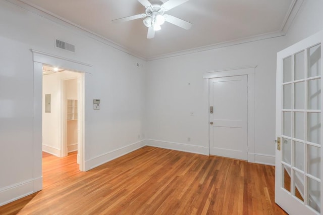 empty room featuring ornamental molding, light wood-style flooring, a ceiling fan, and baseboards