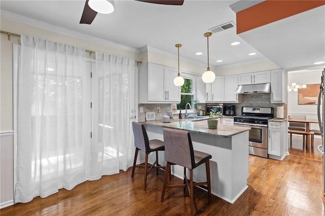 1438 Heritage Glen Dr, Marietta, GA 30068 - kitchen featuring stainless steel gas stove, under cabinet range hood, a peninsula, a ceiling fan, and white cabinetry