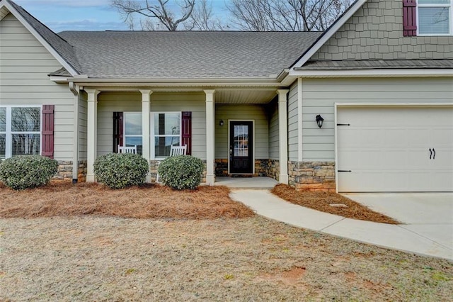 doorway to property with stone siding, a shingled roof, a porch, and concrete driveway