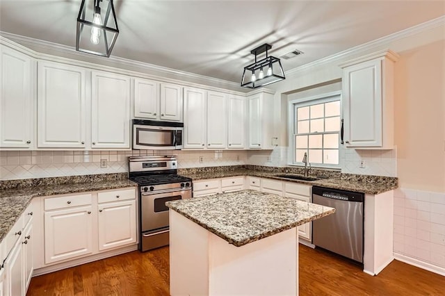 1713 Paramore Pl NE, Marietta, GA 30062 - kitchen with appliances with stainless steel finishes, white cabinets, a kitchen island, and ornamental molding