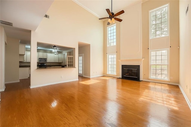 1713 Paramore Pl NE, Marietta, GA 30062 - unfurnished living room featuring ceiling fan, a high ceiling, plenty of natural light, light wood-style flooring, and ornamental molding