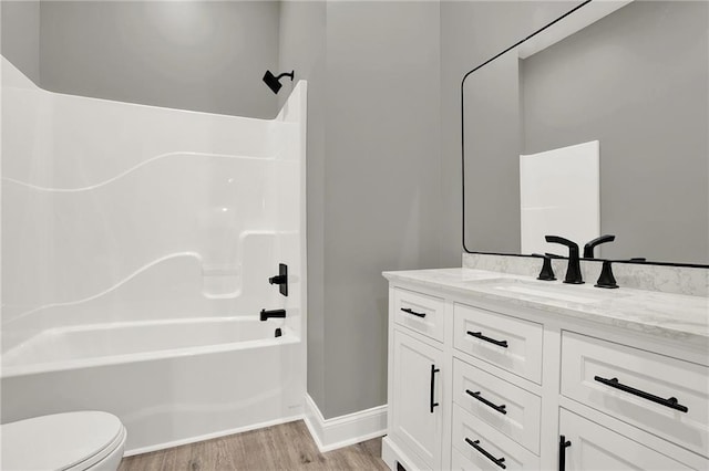 full bathroom featuring toilet, wood finished floors, shower / bath combination, baseboards, and vanity