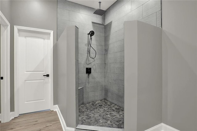 bathroom with baseboards, wood finished floors, and a walk in shower