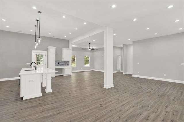 unfurnished living room with a ceiling fan, baseboards, dark wood finished floors, recessed lighting, and a sink