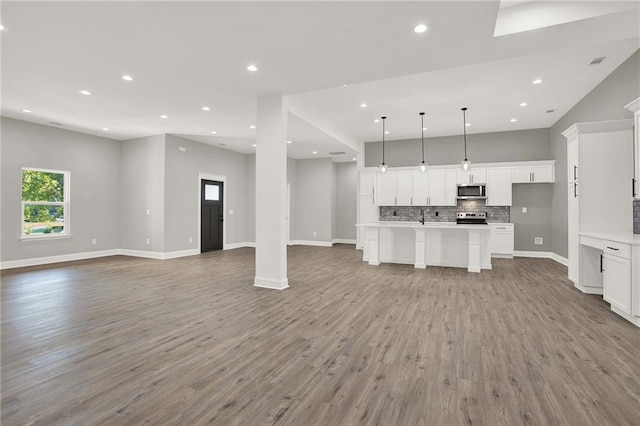 kitchen with open floor plan, backsplash, white cabinets, and wood finished floors