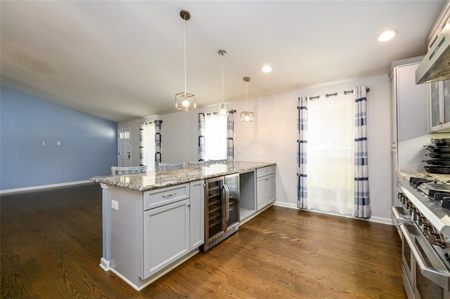 kitchen featuring dark hardwood / wood-style floors, beverage cooler, double oven range, hanging light fixtures, and light stone counters