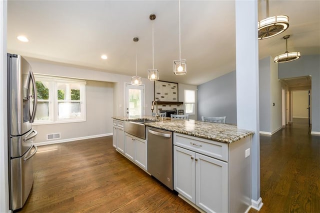 kitchen with decorative light fixtures, white cabinets, appliances with stainless steel finishes, and sink