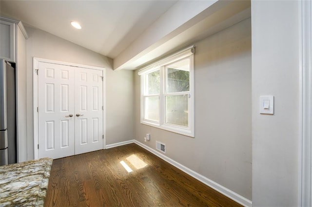 unfurnished bedroom with dark wood-type flooring, vaulted ceiling, and a closet