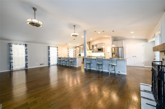 living room with a healthy amount of sunlight, vaulted ceiling, dark hardwood / wood-style flooring, and a fireplace