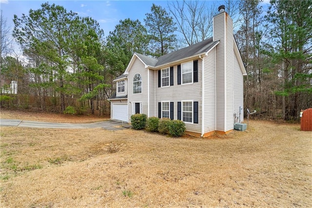 view of home's exterior with a garage, driveway, and a chimney