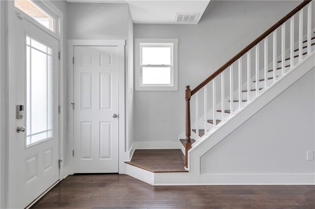 foyer entrance featuring stairs, plenty of natural light, dark wood-type flooring, and baseboards