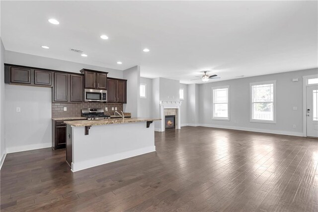 kitchen featuring stainless steel appliances, a ceiling fan, a kitchen bar, baseboards, and recessed lighting
