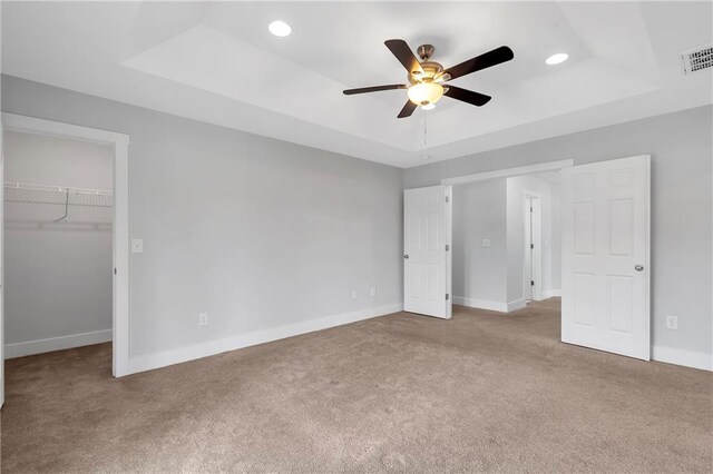 unfurnished bedroom with a raised ceiling, carpet floors, and recessed lighting