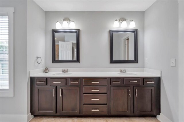 full bathroom featuring double vanity and baseboards