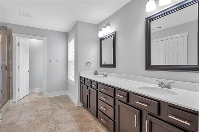bathroom featuring double vanity, a shower stall, and baseboards