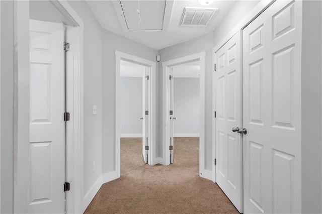 hallway with carpet flooring, attic access, and baseboards