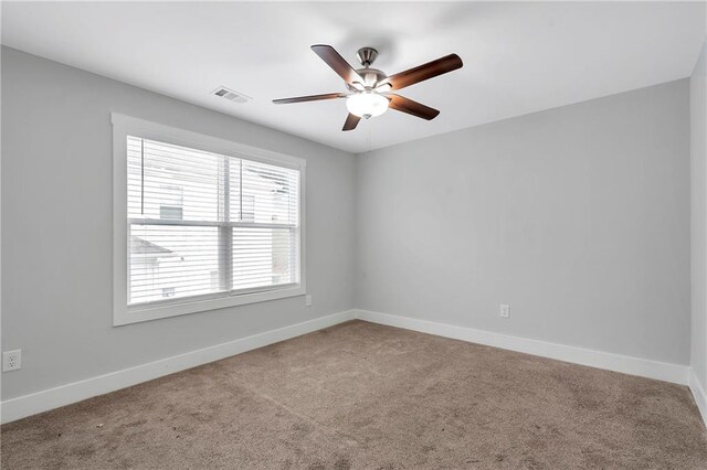 carpeted empty room featuring a ceiling fan and baseboards