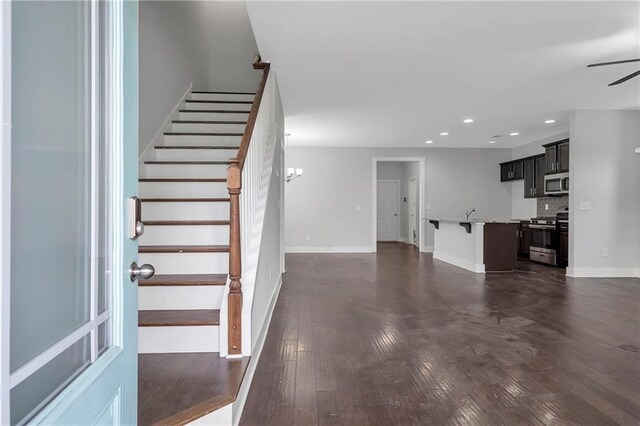 unfurnished living room with recessed lighting, stairs, a ceiling fan, baseboards, and dark wood-type flooring