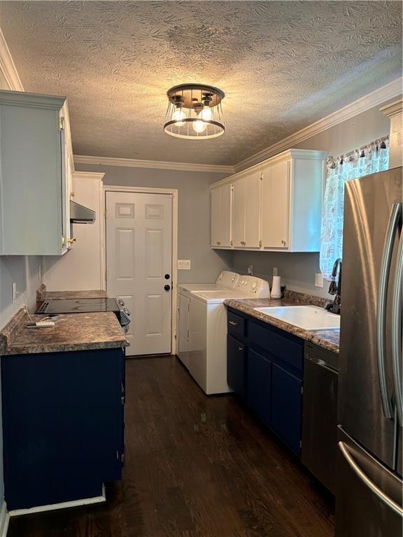 kitchen with white cabinets, sink, independent washer and dryer, stainless steel refrigerator, and crown molding