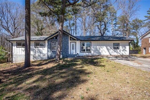 ranch-style house featuring concrete driveway, board and batten siding, and a front yard