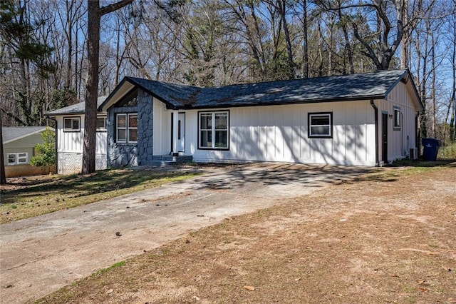 view of front of home with driveway, stone siding, and a front yard