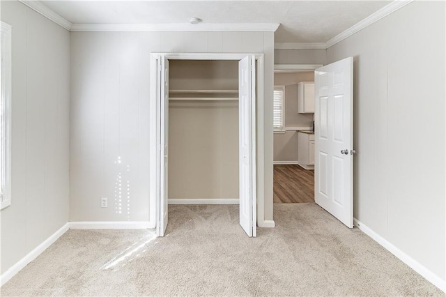 unfurnished bedroom with crown molding, a closet, baseboards, and light colored carpet