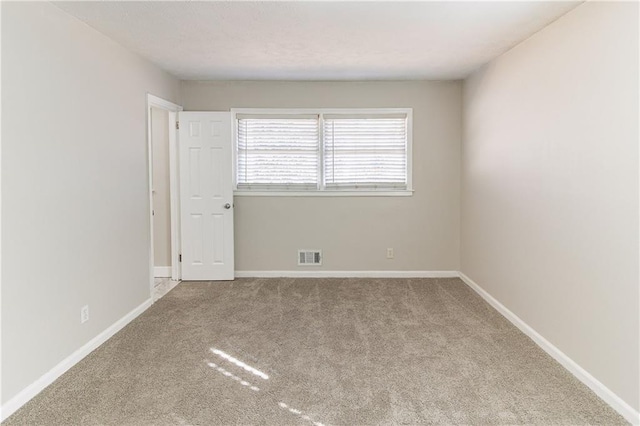 carpeted empty room featuring visible vents and baseboards