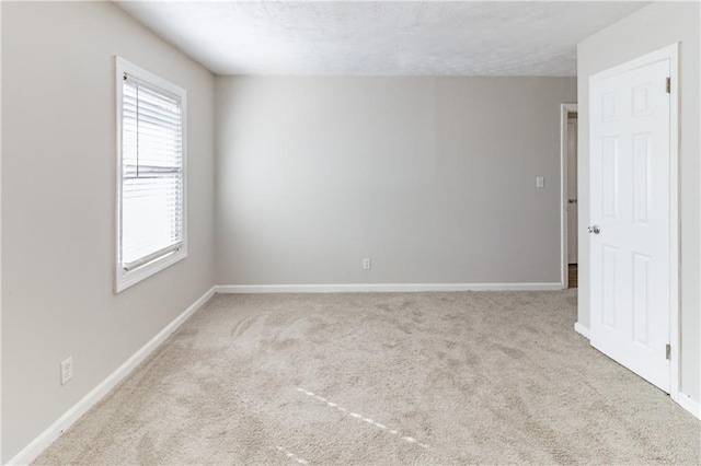 carpeted spare room featuring baseboards and a textured ceiling