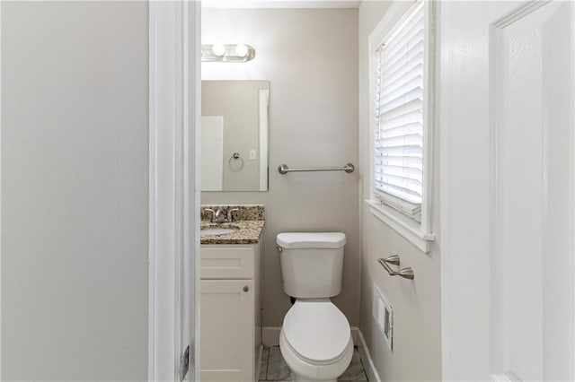 bathroom with baseboards, vanity, and toilet