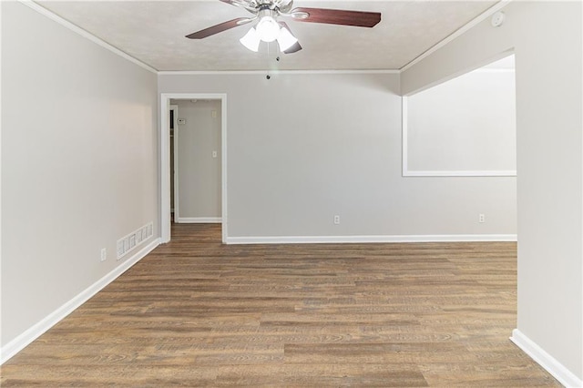 spare room with wood finished floors, visible vents, baseboards, a ceiling fan, and ornamental molding