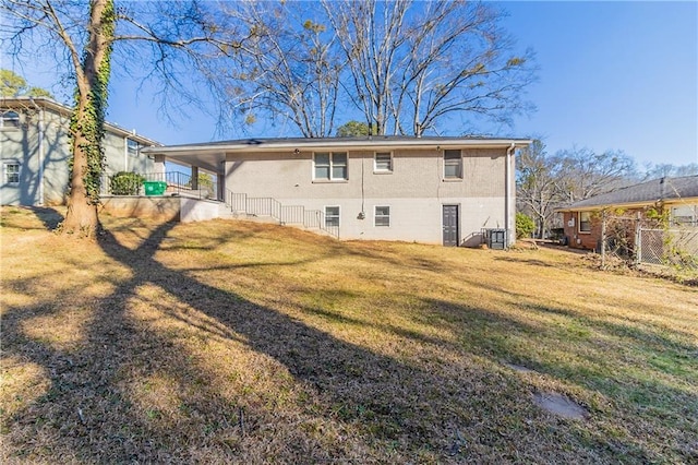 rear view of house with a lawn and fence