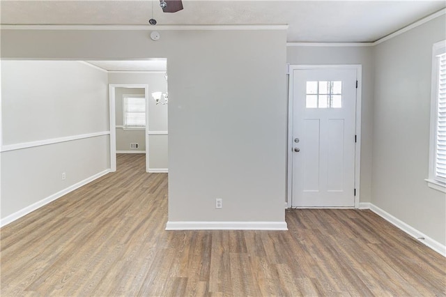 foyer with plenty of natural light, crown molding, and wood finished floors