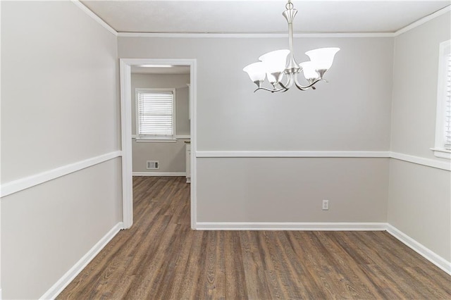 unfurnished dining area featuring crown molding, baseboards, wood finished floors, and an inviting chandelier