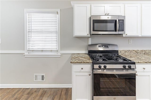 kitchen featuring wood finished floors, visible vents, appliances with stainless steel finishes, white cabinetry, and light stone countertops