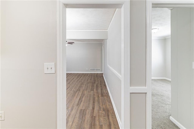 hallway featuring ornamental molding, visible vents, a textured ceiling, and baseboards