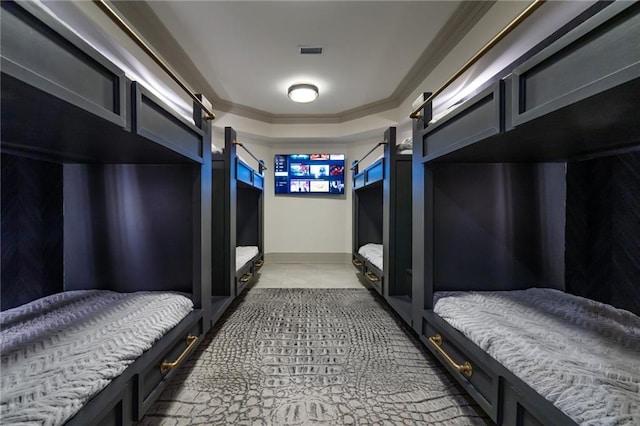 bedroom with light tile patterned floors, a barn door, visible vents, ornamental molding, and a tray ceiling