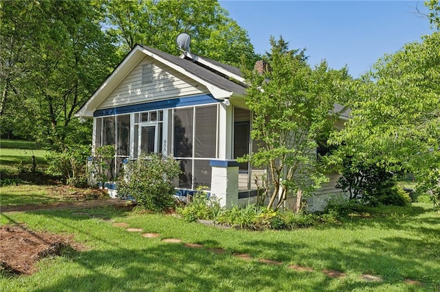 back of property featuring a yard, a sunroom, and a chimney