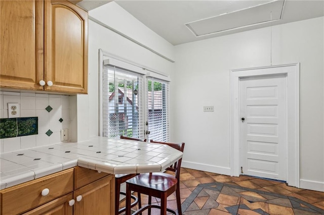 kitchen with backsplash, tile counters, and baseboards